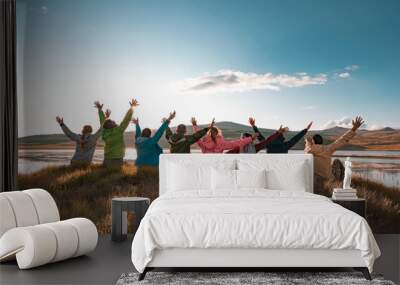 Big group of tourists sits with raised arms at sunset lake Wall mural