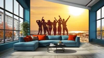 Group of happy young friends are having fun and embracing at sunset beach Wall mural