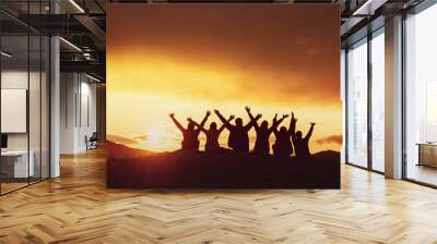 Happy friends with raised arms sunset silhouettes Wall mural