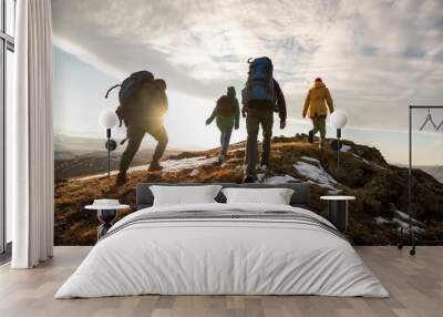 Hikers with backpacks walks in mountains at sunset Wall mural