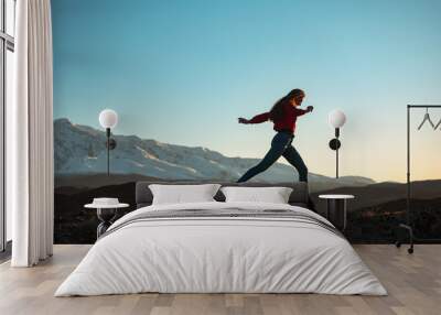 Slim sporty girl walks at sunset in mountains Wall mural