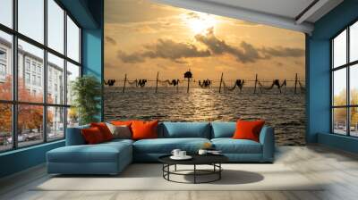 Silhouette of fishermen pulling a nets on fishing poles at sea in Tra Vinh province, Vietnam, Asia during sunrise, local people call it is Day hang khoi. Wall mural