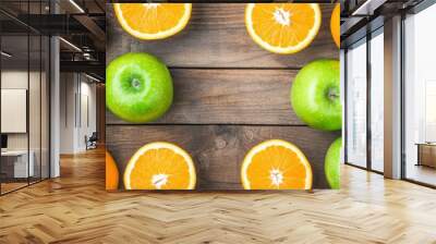 Fresh green apples and a juicy orange on a rustic wooden table create a beautiful contrast of colors and health. Wall mural