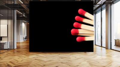 Wooden matches with vibrant red tips await their spark, set against a sleek black backdrop, embodying the essence of fire. Wall mural