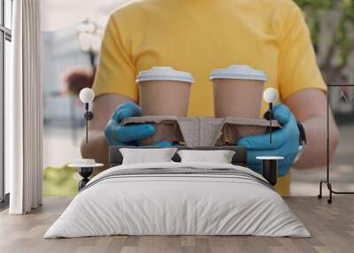 A close up of a man's hands in blue medical gloves holding a carry tray with two cups of morning fragrant coffee. Wall mural