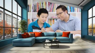 Asian teacher helping his student to read a book Wall mural