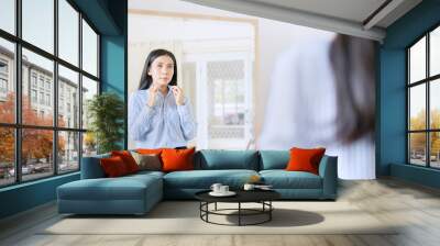 elegant asian businesswoman buttoning up shirt in front of mirror getting ready for work Wall mural