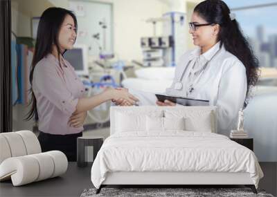 Friendly doctor shaking hands with patient in the clinic Wall mural