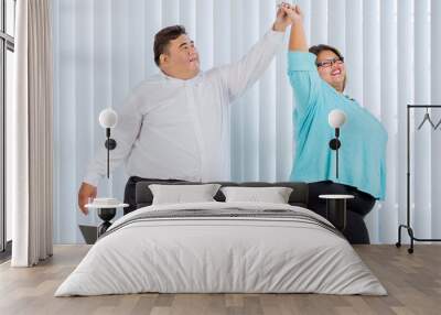 Happy fat business couple dancing in office Wall mural