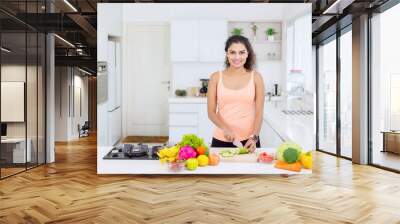 Happy woman cutting vegetables for salad at home Wall mural