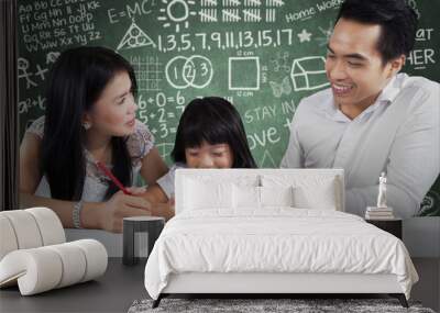 Little girl with parents doing homework Wall mural