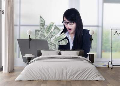 Shocked businesswoman looking money at laptop Wall mural