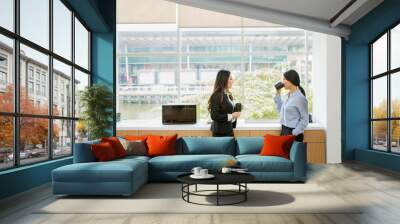 Two businesswomen enjoying coffee time in office Wall mural