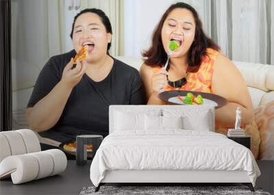 Two fat women having lunch with salad and pizza Wall mural