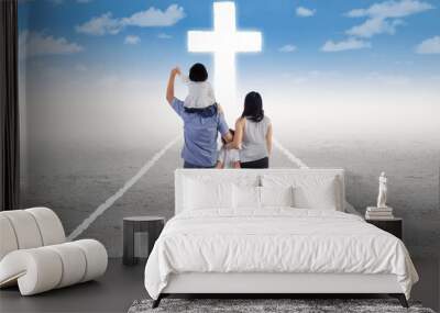 Young family follow a cross on the road Wall mural