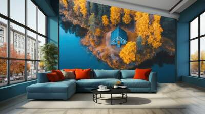 A small blue house sits on a peninsula in a forest filled with golden leaves.  The peninsula is surrounded by a still blue lake. Wall mural