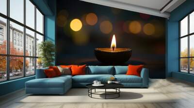 A single candle is lit, casting warm light on the dark background with blurred lights in the distance, Diwali celebration Wall mural