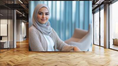 Portrait of a beautiful Middle Eastern businesswoman sitting in an office, wearing a hijab and trendy, relaxing on a modern armchair Wall mural