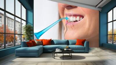 Closeup of woman with perfect smile using water flosser or oral irrigator Wall mural