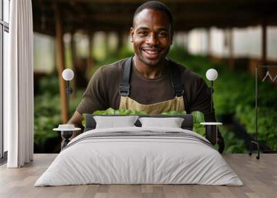 Portrait of a smiling African farmer holding a box of fresh organic vegetables in a hydroponic greenhouse plantation Wall mural