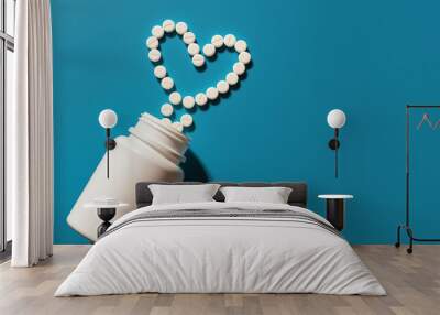 Pills forming heart shape from bottle on blue background for health and wellness concept Wall mural