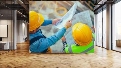 Above view of a construction professional consulting with the building engineer over project plan in work site with hard hat safety. Blueprint review by construction specialists on site. Wall mural