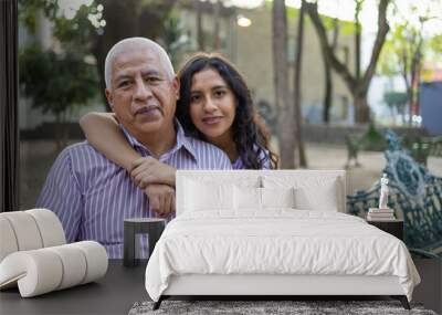 Portrait of grandfather and granddaughter sitting in a bench. Wall mural