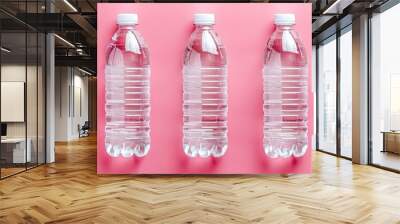 Clear plastic bottles filled with water in the photo in front of a pink wall Wall mural