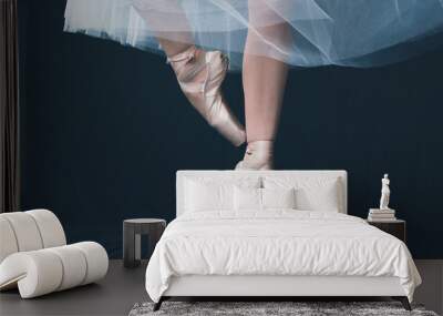 Close-up of dancing legs of ballerina wearing white pointe on a black background. Wall mural