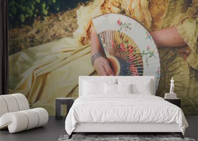 Luxurious medieval hand fan in the female hand, close up. Baroque accessory. Selective focus Wall mural