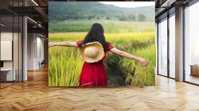 Girl walking in a rice field wearing red dress Wall mural