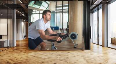 Man exercising in the gym riding stationary bike indoor cycling Wall mural