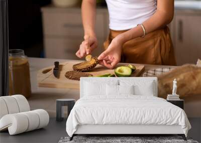 Woman making avocado peanut butter toast for a healthy breakfast Wall mural