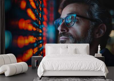 A man with glasses is looking at a screen with a lot of numbers on it. He is focused and attentive Wall mural