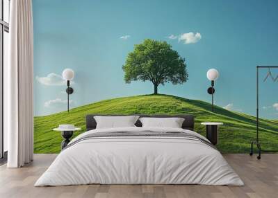 A solitary ash tree on a bright green hill under a clear sky with scattered clouds, symbolizing solitude and peace. Wall mural