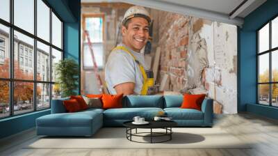 Happy latino construction worker wearing a hardhat working in a home, house renovation and builder concept Wall mural