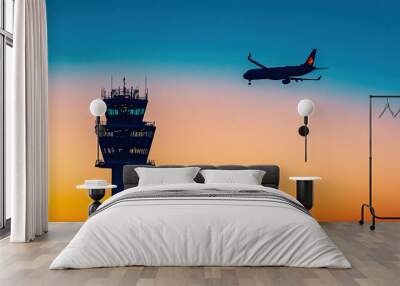 Silhouette of an airplane flying over the control tower at sunset Wall mural