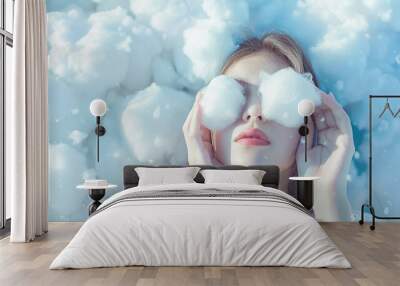 Dreamy scene with a woman holding fluffy cotton balls over her eyes, on a soft Wall mural