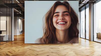 Minimalistic photo of a young woman standing against a light background, laughing and smiling. Clean and simple image with ample copy space.
 Wall mural