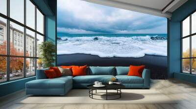 Vast ocean landscape, rolling waves crashing gently on a black sand beach, dramatic clouds in the sky, wide panoramic shot, moody atmosphere Wall mural