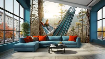 Young happy man relaxing lying in hammock on top of mountain. Wall mural