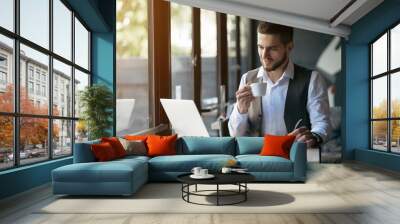 Young businessman working on a plan of Internet project on the laptop. Man discusses business matters by phone. Working computer for internet research. Digital marketing. Development Wall mural