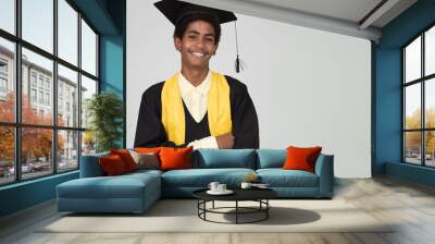 Portrait of graduate teen latin boy student in black graduation gown with hat - isolated on background. Child back to school and educational concept. Wall mural