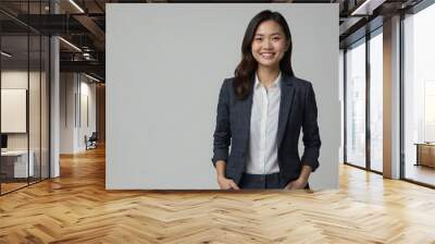 
Asian woman with smile on her face next to empty space on dark gray background. Beautiful young woman in stylish clothes in a studio with place for advertising text. Wall mural