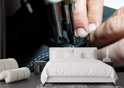 Close up view of Upholsterer's hands sewing leather parts with a sewing machine to fix a seat. Wall mural