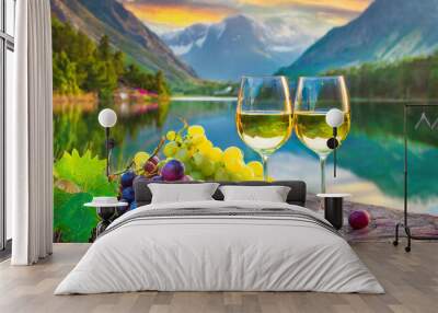 Deux verres de vin blanc et des grappes de raisin au bord d'un lac de montagne.  Wall mural