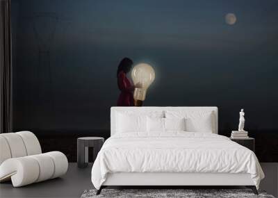 woman embraces one of her creative idea lighting up the night, power concept Wall mural