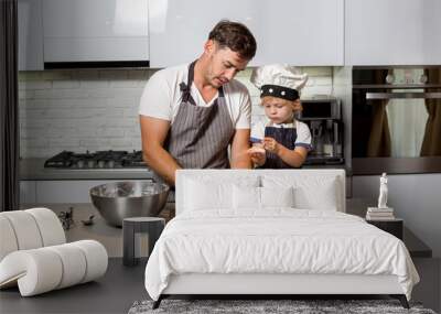 Dad and son kneading dough on the kitchen table. Wall mural