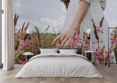 Hand of woman touching blossoming flowers in a flower field moody atmosphere Wall mural