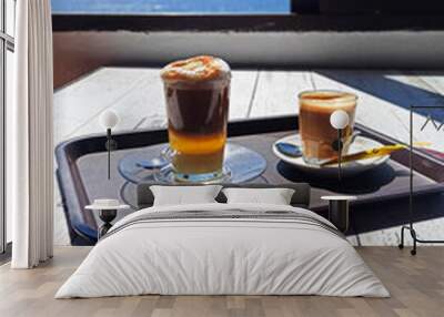 Hot drinks on a tray. A coffee with milk and a Barraquito or zaperoco coffee: a very popular sweet coffee drink in the Canary Islands made up of condensed milk, liquor, espresso coffee and foamed milk Wall mural